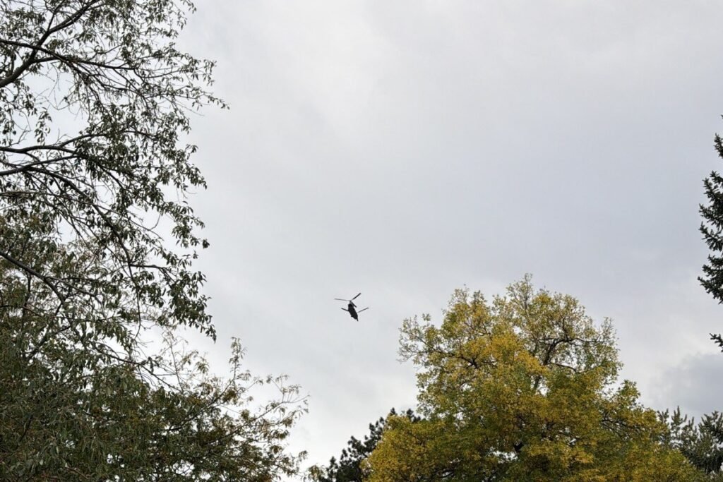 A military helicopter flying low over treetops near Green Mountain
