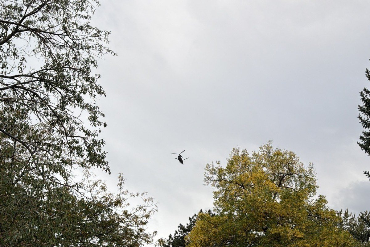 A military helicopter flying low over treetops near Green Mountain